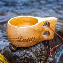 Träkåsan är handgjord av trä, så att varje kåsa är helt unik. Stilig design och enkel att hålla i. Skinnremmen gör att den är perfekt att fästa utanpå ryggsäcken. Kåsan är lik älgkåsan, men utan älgen på baksidan.

Lasergraveras med valfritt nam.